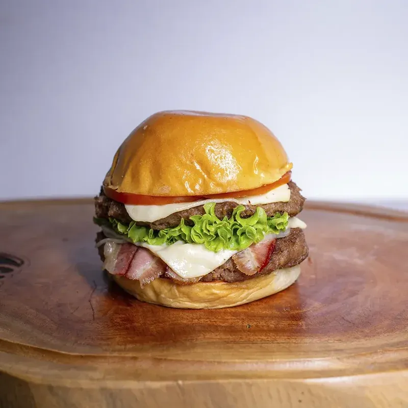 Hambúrguer artesanal da Lac Lanches com bacon e queijo no pão brioche
